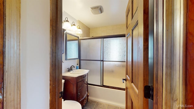 bathroom with vanity, tile patterned flooring, bath / shower combo with glass door, and toilet