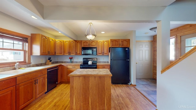 kitchen featuring a sink, a kitchen island, black appliances, and a healthy amount of sunlight