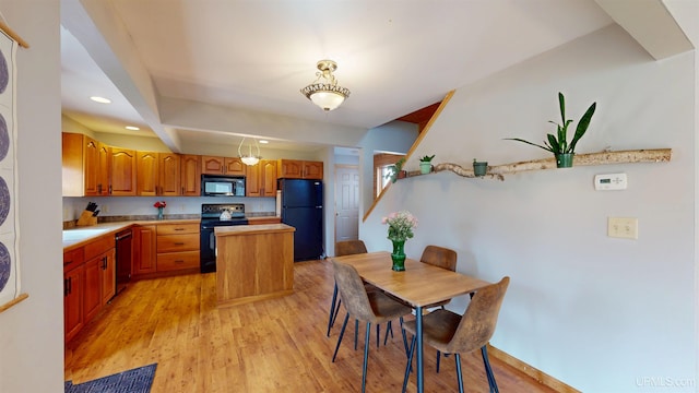 kitchen featuring light wood-style floors, light countertops, a kitchen island, and black appliances