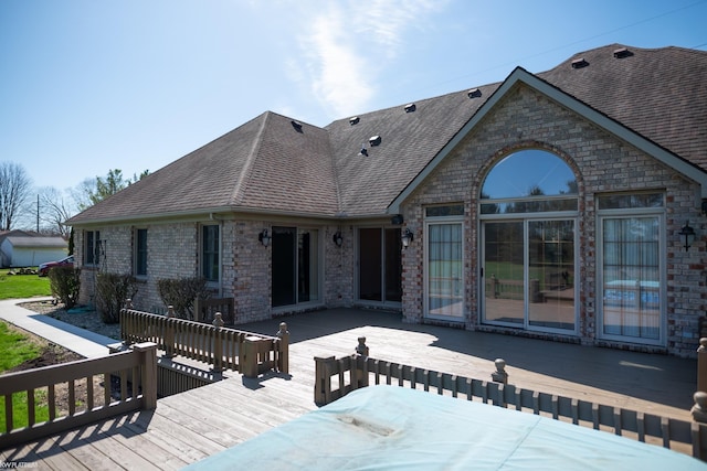 rear view of property with roof with shingles and a deck