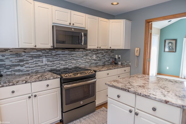 kitchen featuring light stone counters, decorative backsplash, appliances with stainless steel finishes, and white cabinets