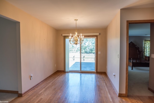unfurnished dining area featuring baseboards, a notable chandelier, and light wood-type flooring