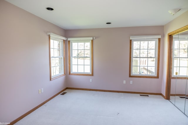 unfurnished room featuring visible vents, baseboards, and light carpet