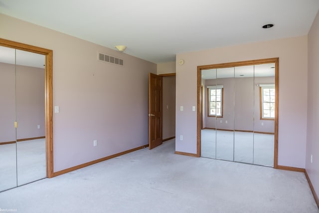 unfurnished bedroom featuring baseboards, light colored carpet, and visible vents