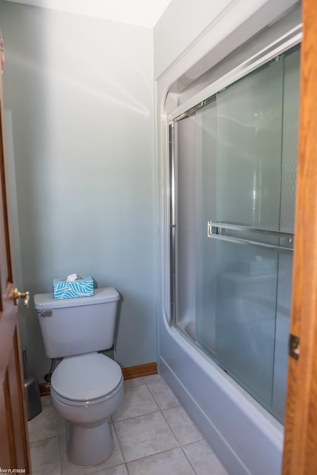 full bathroom with baseboards, combined bath / shower with glass door, tile patterned floors, and toilet
