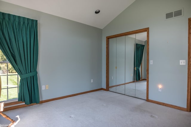 unfurnished bedroom featuring visible vents, vaulted ceiling, carpet floors, baseboards, and a closet
