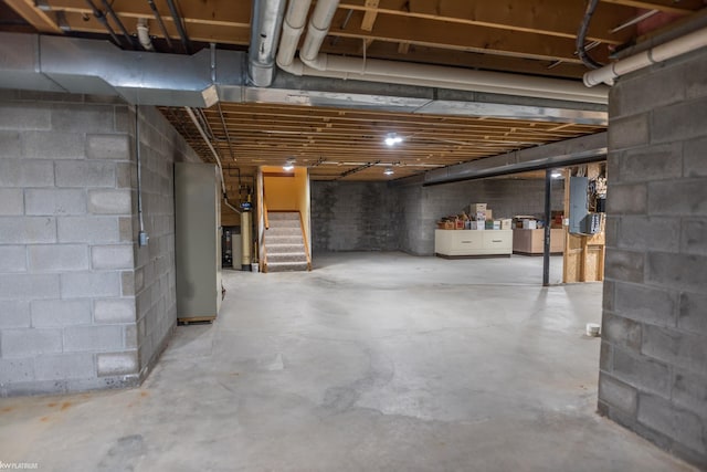 unfinished basement featuring stairs, electric panel, and concrete block wall