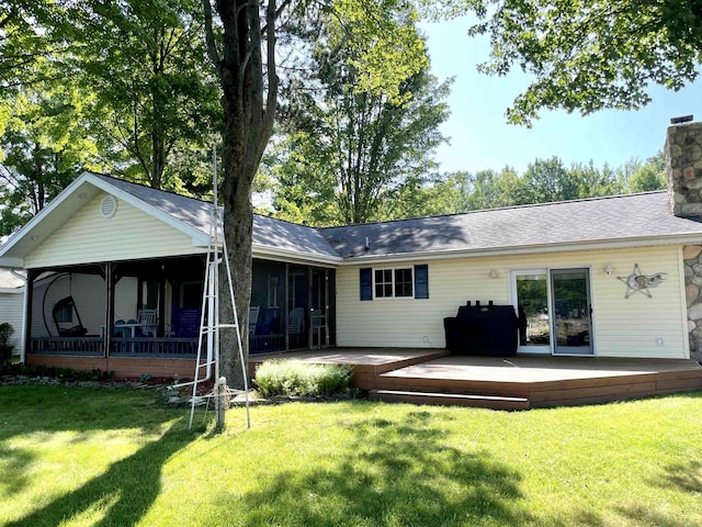 back of house featuring a yard, a chimney, a sunroom, and a wooden deck