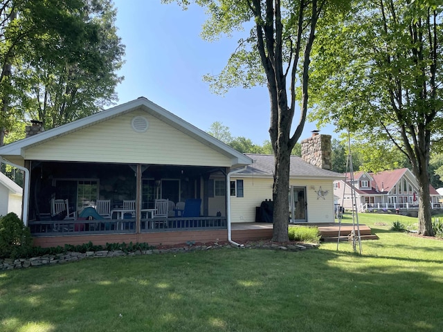 back of property with a sunroom, a chimney, and a yard