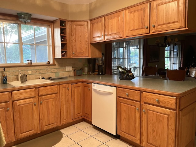 kitchen with white dishwasher, plenty of natural light, light tile patterned flooring, and a peninsula