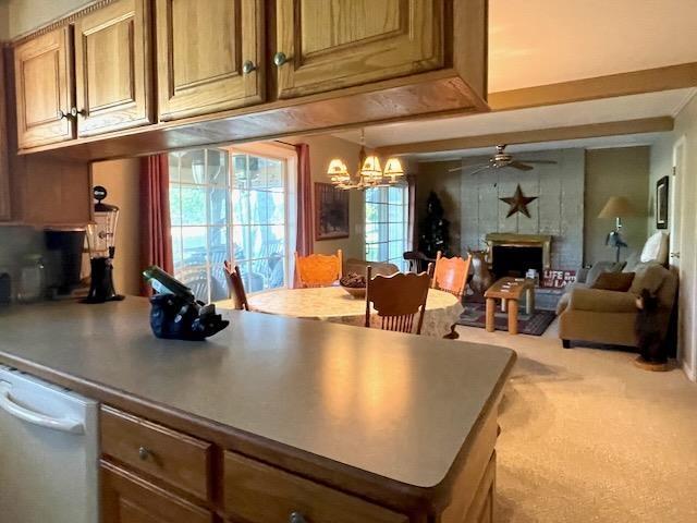 kitchen featuring a fireplace, ceiling fan with notable chandelier, carpet flooring, and open floor plan