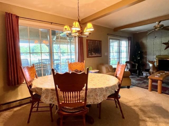 carpeted dining room featuring ceiling fan with notable chandelier, a wood stove, and beam ceiling