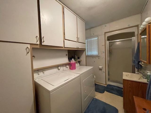 washroom with cabinet space, washing machine and dryer, and a sink
