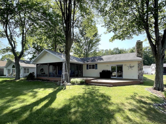 back of house with a lawn, a wooden deck, a chimney, and a sunroom