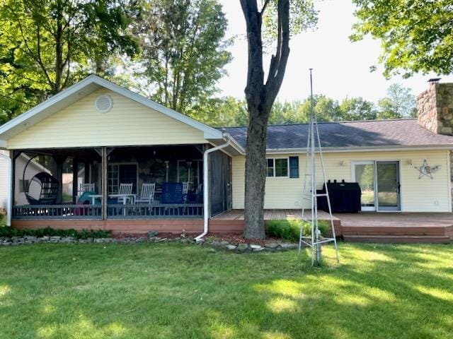 rear view of property featuring a wooden deck, a yard, and a chimney