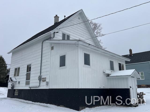 snow covered property with a chimney