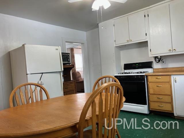kitchen featuring range with gas cooktop, a ceiling fan, light countertops, freestanding refrigerator, and white cabinetry
