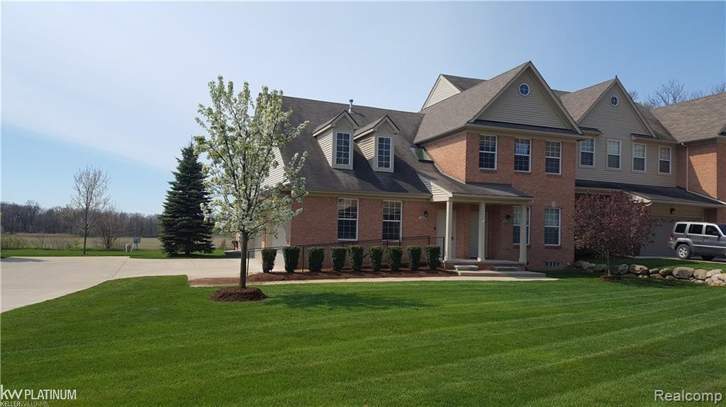 view of front of house with brick siding, a front yard, and concrete driveway
