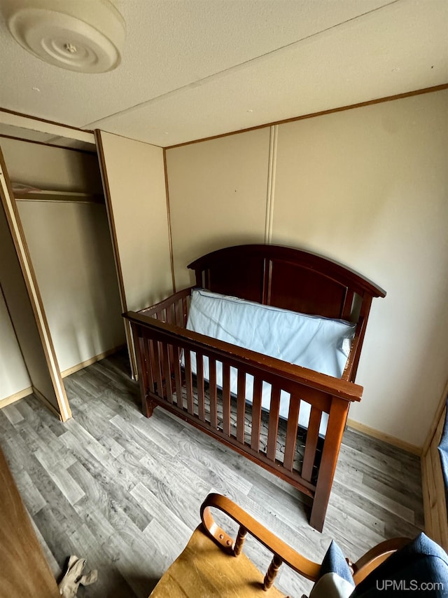 bedroom featuring baseboards, wood finished floors, and a closet