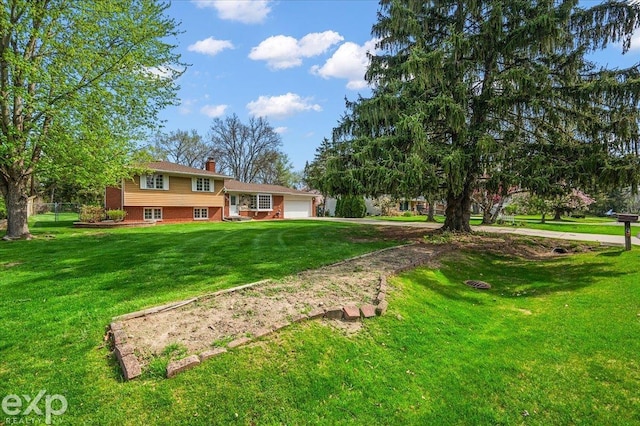 view of yard with fence, an attached garage, and driveway