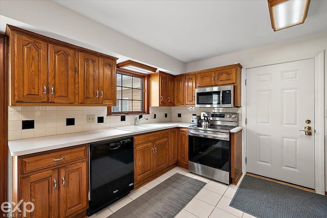 kitchen featuring light countertops, brown cabinets, tasteful backsplash, a sink, and stainless steel appliances