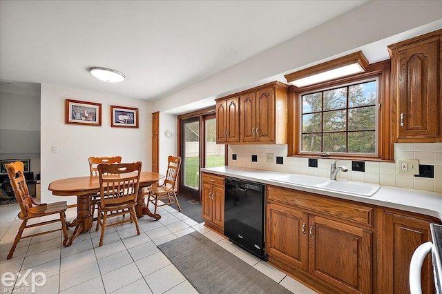 kitchen with black dishwasher, brown cabinetry, a wealth of natural light, and a sink