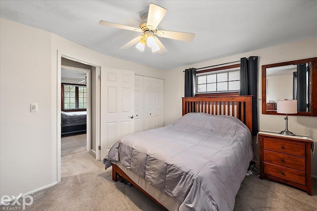 bedroom with baseboards, ceiling fan, light carpet, and a closet