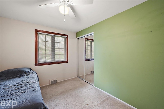 carpeted bedroom featuring baseboards, visible vents, ceiling fan, and a closet