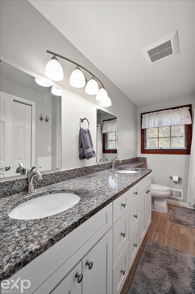 bathroom featuring toilet, visible vents, and a sink