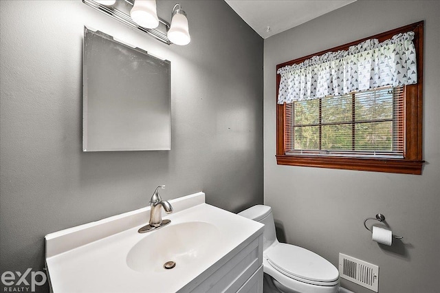 half bath with toilet, visible vents, and vanity