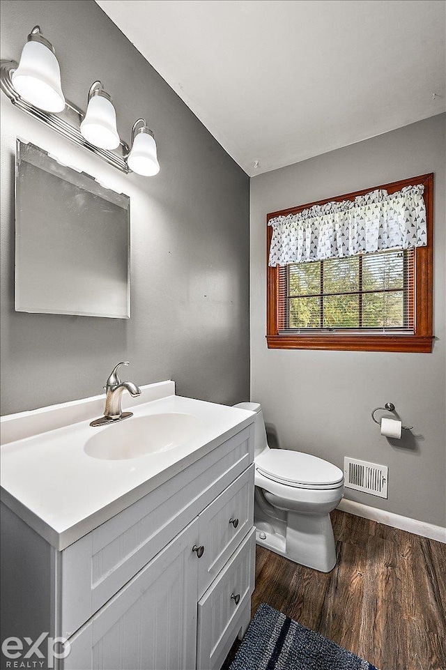 bathroom featuring vanity, visible vents, wood finished floors, toilet, and baseboards