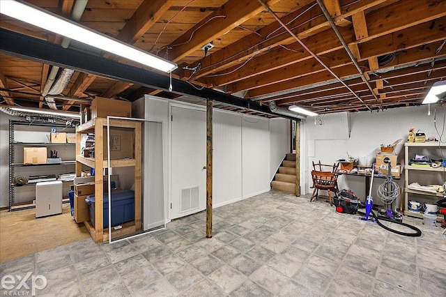 unfinished basement featuring visible vents and stairway