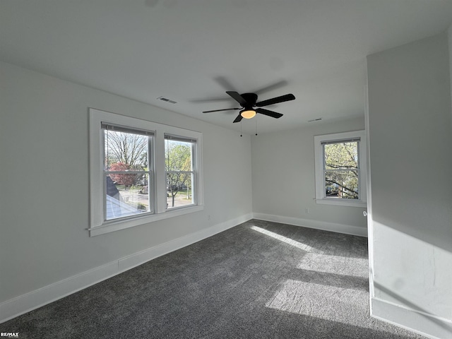 unfurnished room featuring baseboards, ceiling fan, dark colored carpet, and visible vents