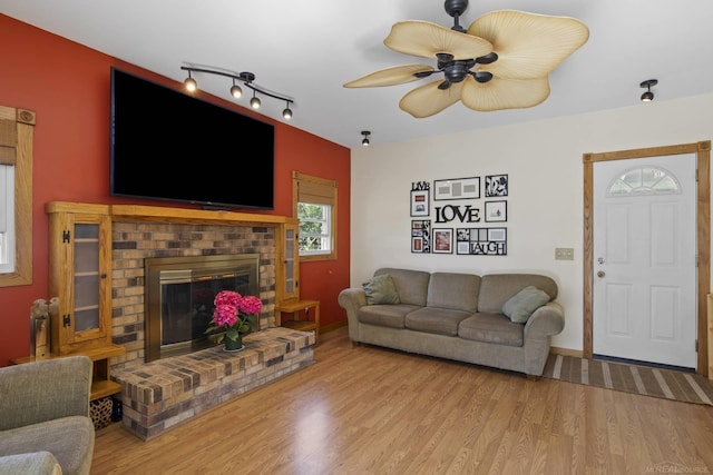 living area featuring ceiling fan, wood finished floors, and a fireplace