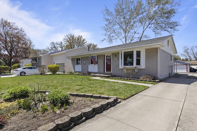 view of front of house with a detached garage, an outbuilding, a front yard, and brick siding