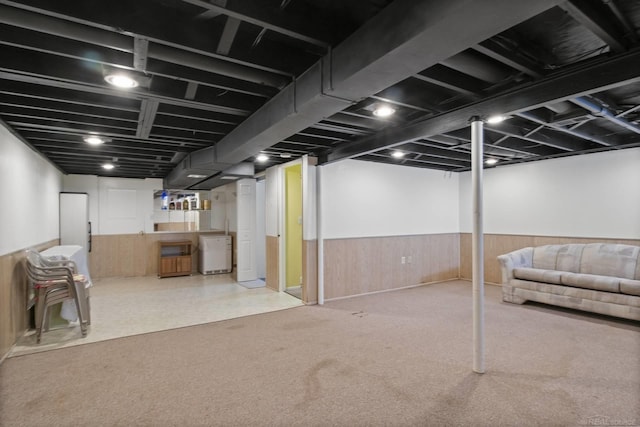 finished basement featuring carpet floors, wood walls, wainscoting, and refrigerator