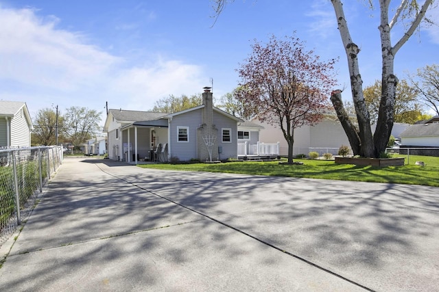 exterior space with concrete driveway, a lawn, fence, and a chimney