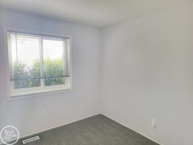 carpeted spare room with visible vents and baseboards