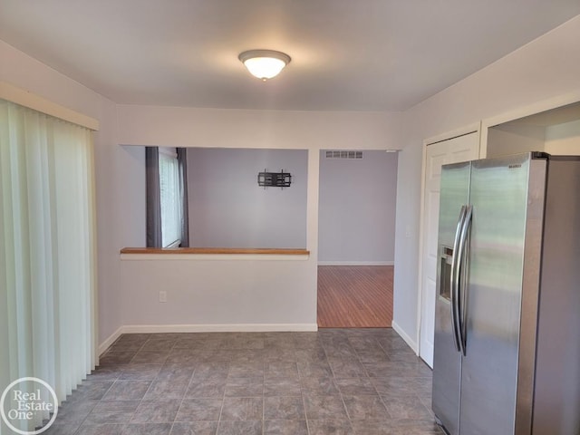 interior space with visible vents, baseboards, and stainless steel fridge with ice dispenser