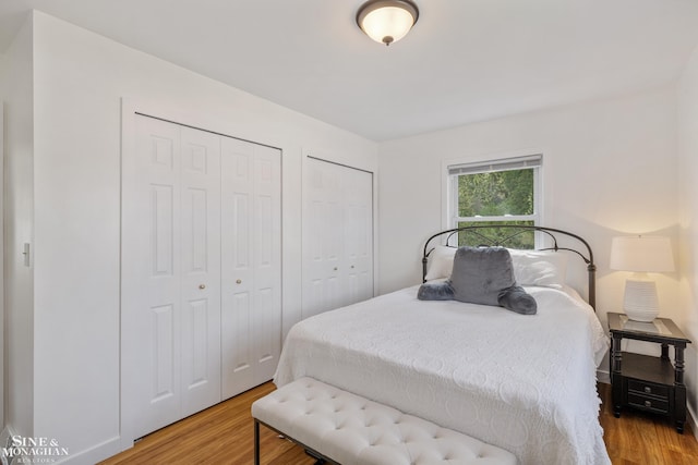 bedroom featuring wood finished floors and two closets