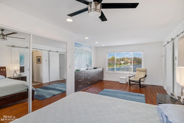bedroom featuring a ceiling fan, a barn door, baseboards, recessed lighting, and dark wood-type flooring
