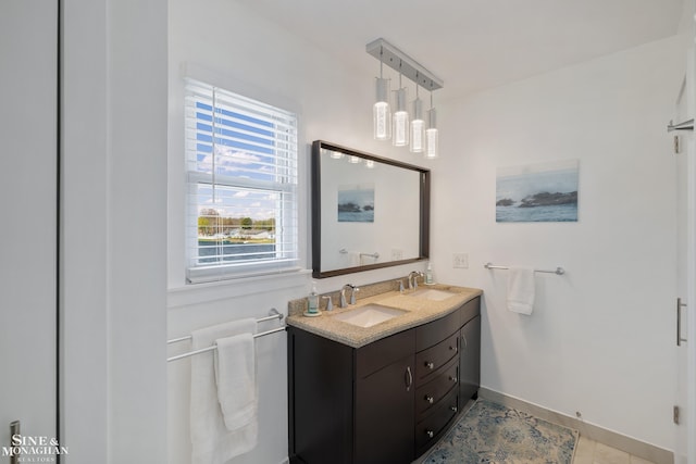 bathroom featuring double vanity, baseboards, and a sink