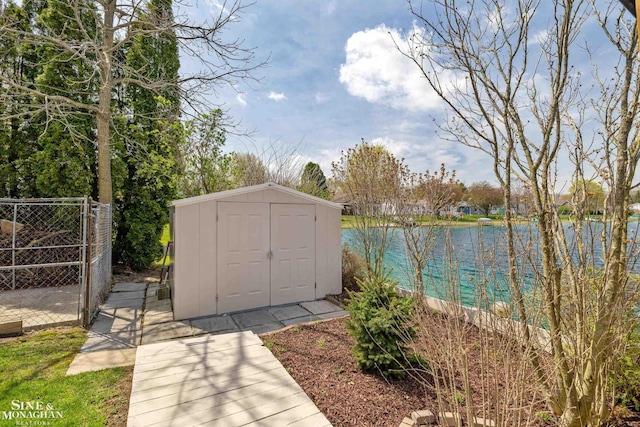 view of shed featuring a water view, fence, and a gate