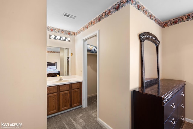 hall featuring a sink, baseboards, dark carpet, and visible vents