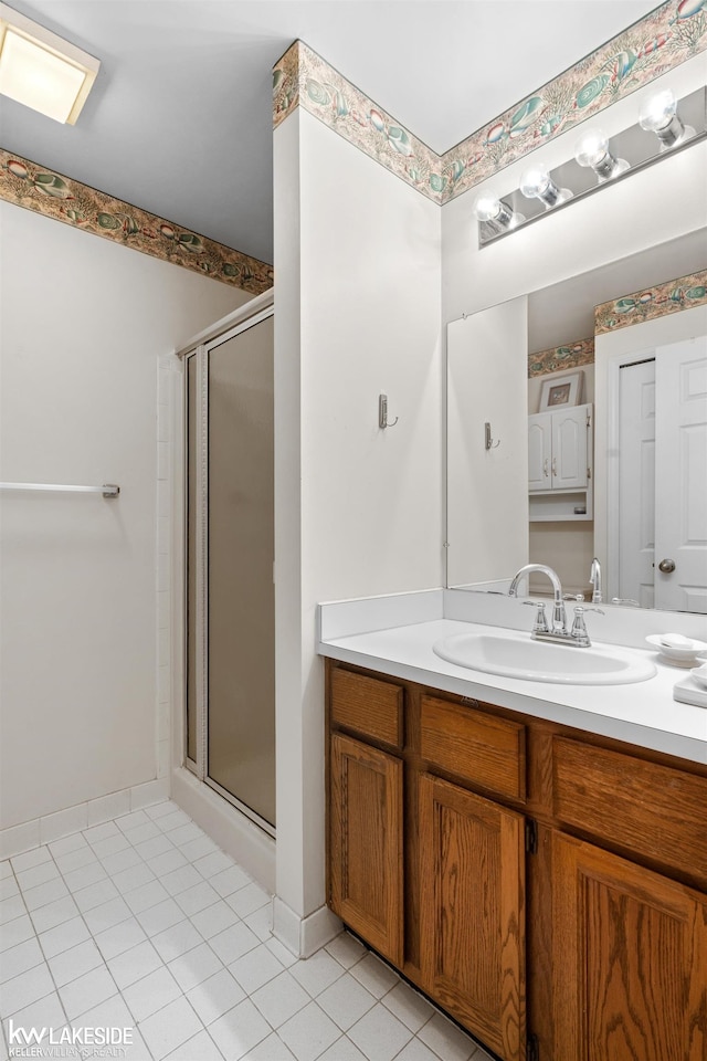 bathroom with vanity, baseboards, tile patterned floors, and a shower stall