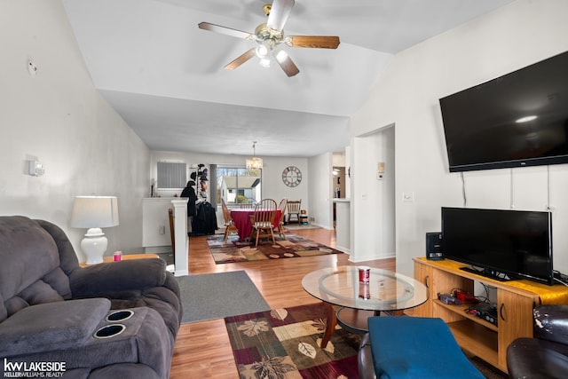 living area featuring light wood-style floors, ceiling fan with notable chandelier, and vaulted ceiling