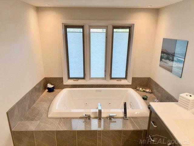 full bathroom featuring a jetted tub and vanity