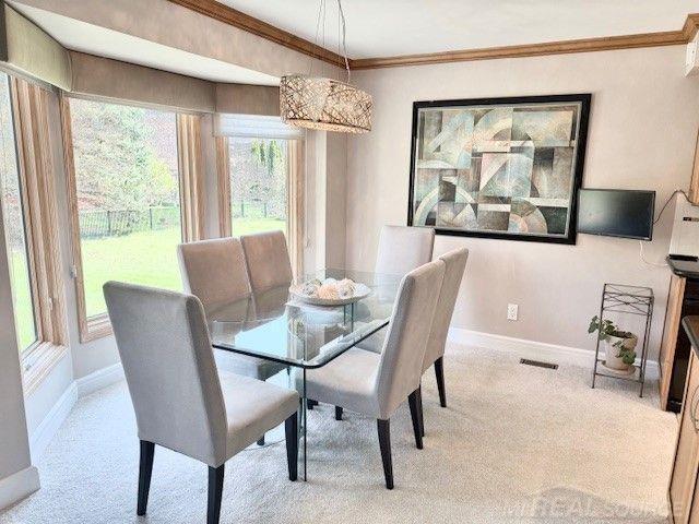 dining room featuring baseboards, carpet, crown molding, and visible vents