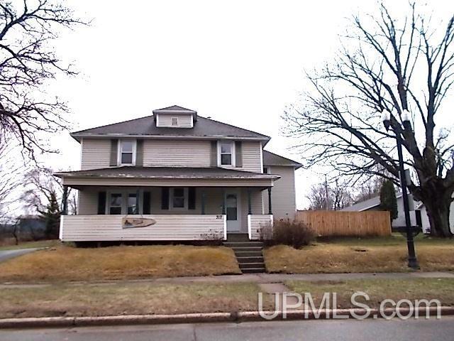 american foursquare style home featuring covered porch and fence