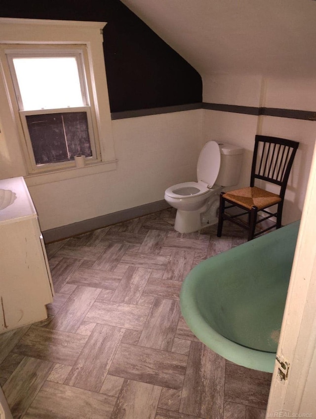 bathroom with toilet, baseboards, and vaulted ceiling